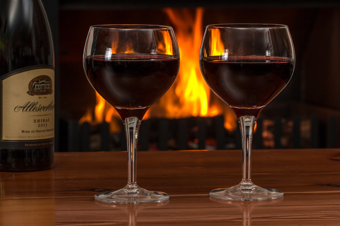 wine glasses in front of a crackling fire